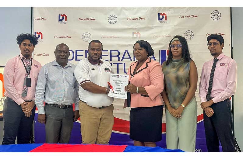 Oceola Van Doimen, Sales and Marketing Coordinator of Demerara Mutual making a presentation to Petra Director Troy Mendonca, flanked by staff of both companies