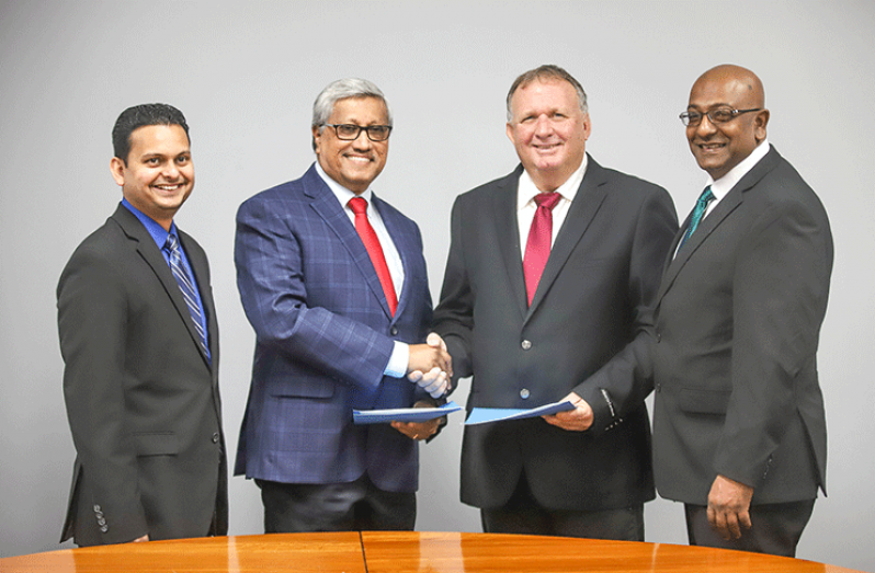DDL Chairman, Komal Samaroo and CWSL CEO, Nigel Bennett shake hands after the signing of an agreement. Vasudeo Singh, DDL Finance Controller and Darren Debideen, CWSL Chief Marketing Officer look on
