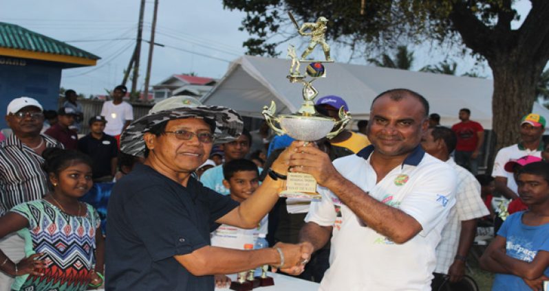 Head Teacher of Crabwood Creek Primary School, Clement Edwards hands over the Mohan and Meena Memorial Trophy to Floodlight Legend skipper Ricky Deonarine.