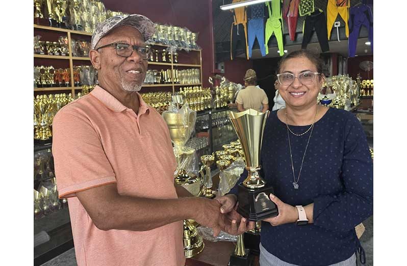 Devi Sunich, wife of Trophy Stall proprietor, Ramesh Sunich, hands over one of the trophies to Frederick Halley who also represented International 6