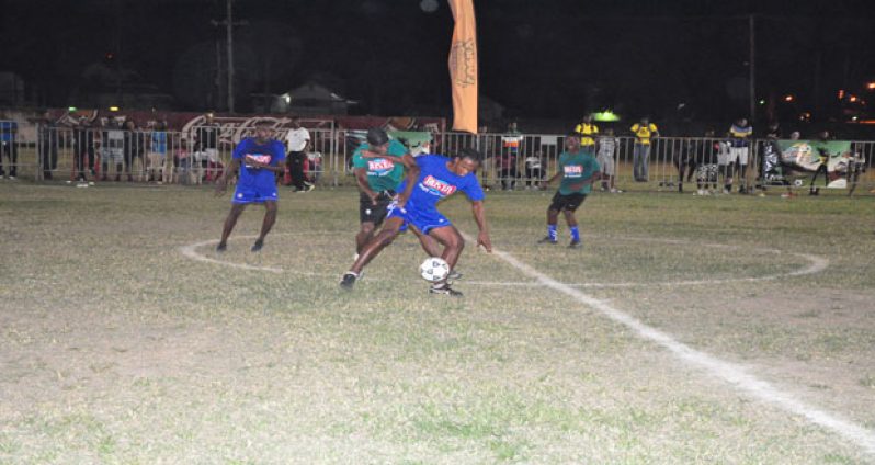 Sparta Boss’ Devon ‘Don Don’ Millington (left, blue top) looks on as his prolific striker Gregory ‘Jackie Chan’ Richardson battles for possession of the ball with this opposing player from Globe Yard, during their epic round-of-16 clash last Sunday night.