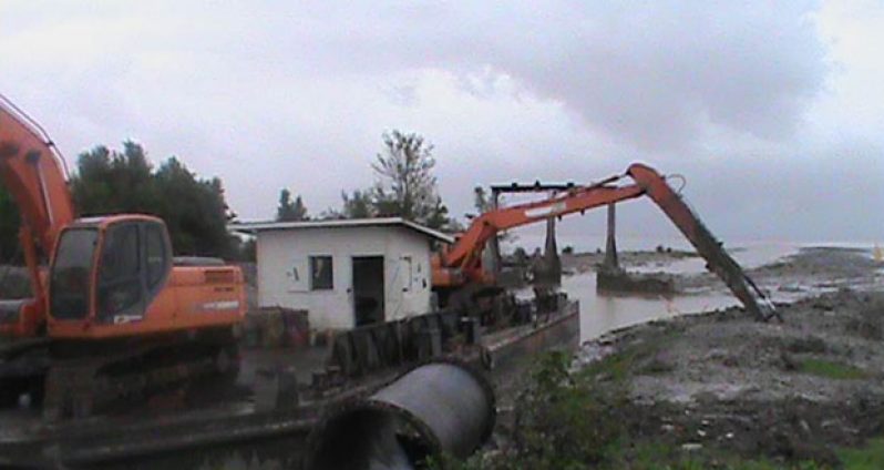 The excavators on a pontoon clearing a silted-up channel on the Essequibo Coast