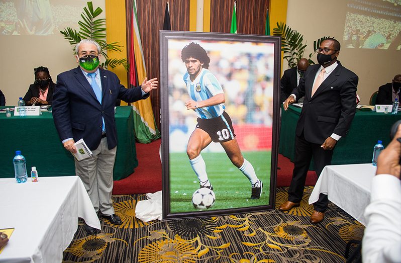 Ambassador Felipe Gardella (left) and GFF President Wayne Forde unveil the tribute to Diego Maradona at the Pegasus Hotel’