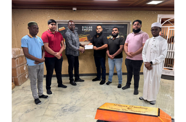 Manager of Dinar’s Trading, Sayad Ahamad, hands over the sponsorship cheque to Aubrey ‘Shanghai’ Major in the presence of staff members