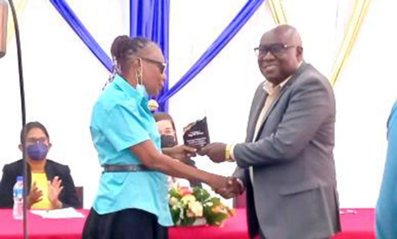Chief Education Officer Marcel Hutson honours Ingrid Peters for being the longest-serving blind educator in Guyana