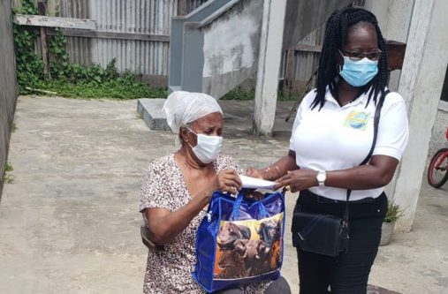 A resident of Lodge Housing Scheme receiving a hamper from a member of the local group