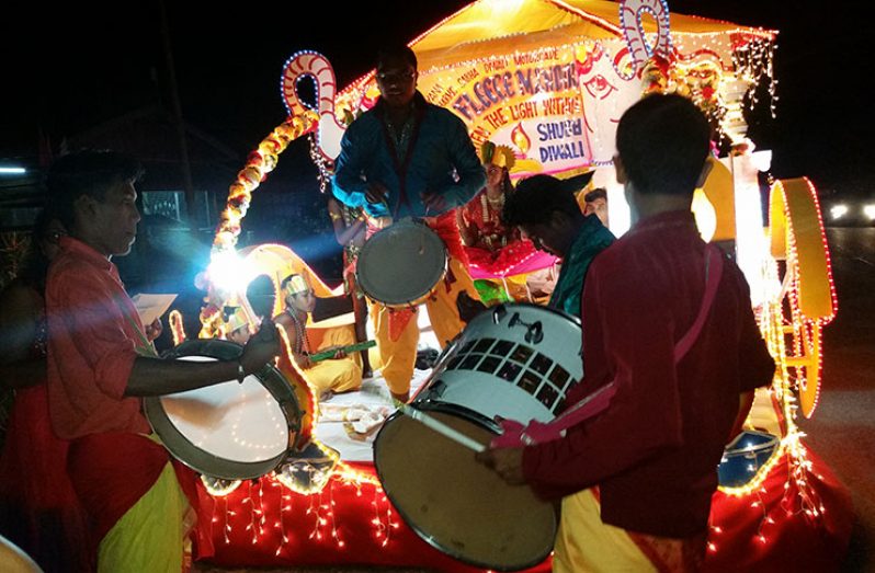 Youths from a Mandir performing live Tassa drumming in front of their float.