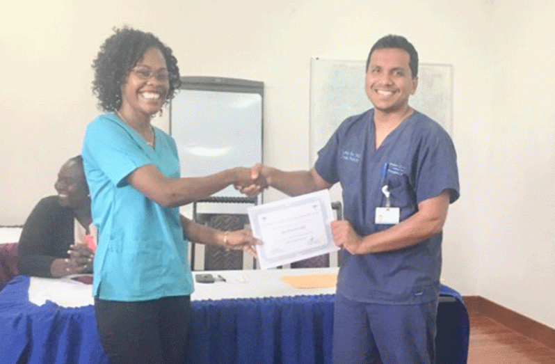 Dr. Zulfikar Bux hands over a certficate to Dr Patricia Hope, following the completion of a triage training course