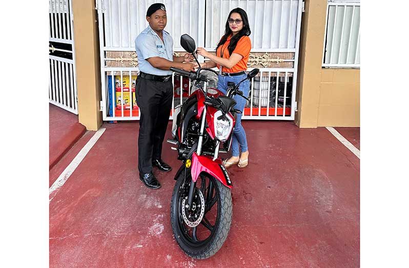 Troy Drakes, left, collects the motorcycle from GSCL Secretary Telesha Ousman Yamin