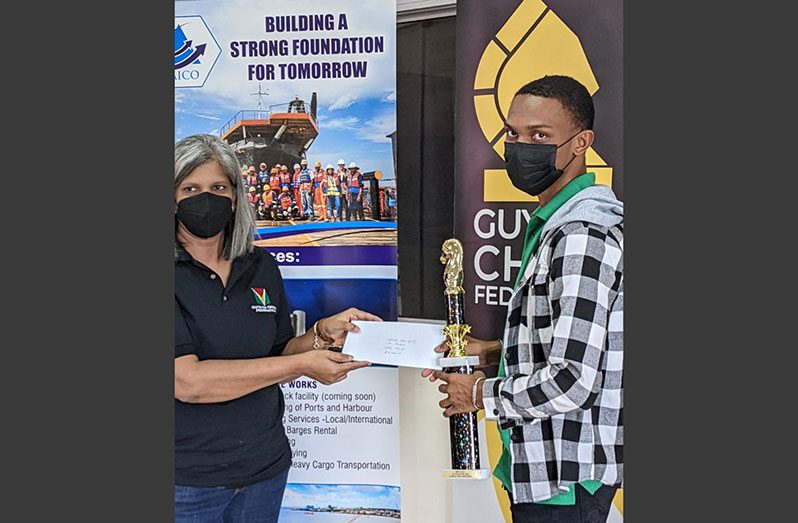 FIDE Master Anthony Drayton (right) receives the winner's prizes from the GCF executive member Mrs Marcia Lee