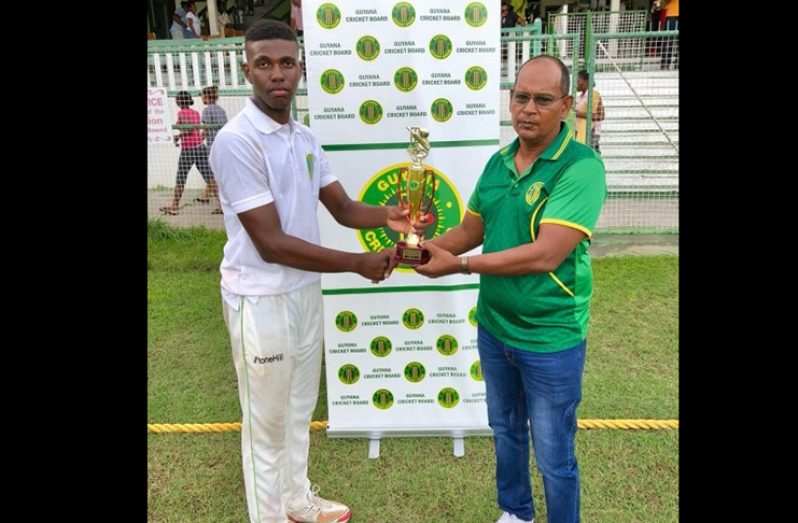 Nazimul Drepaul hands over the man-of-the-match trophy to Seon Glasgow for his hundred against the National Select Under-15 team during the just concluded Inter-county Under-17 tournament.