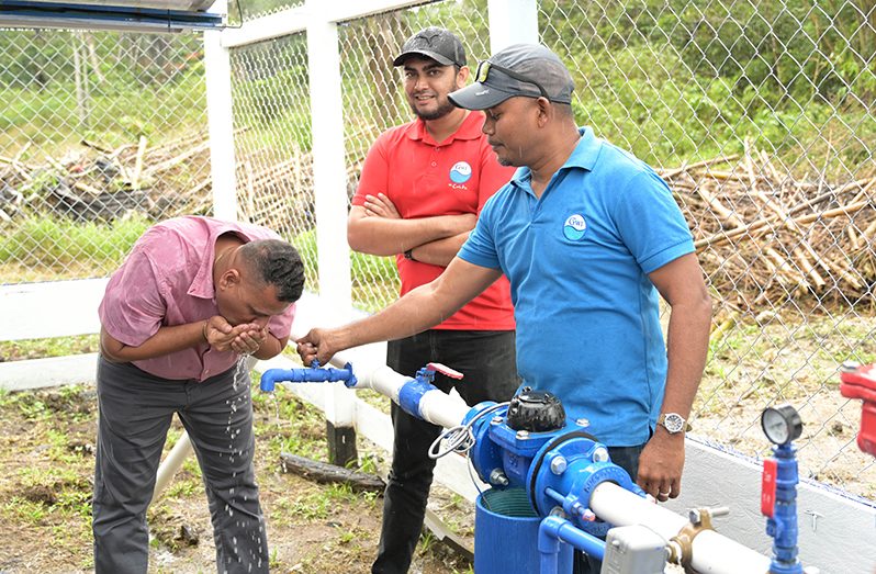 Minister of Housing and Water, Collin Croal drinks water after commissioning the Huradiah Water Supply System