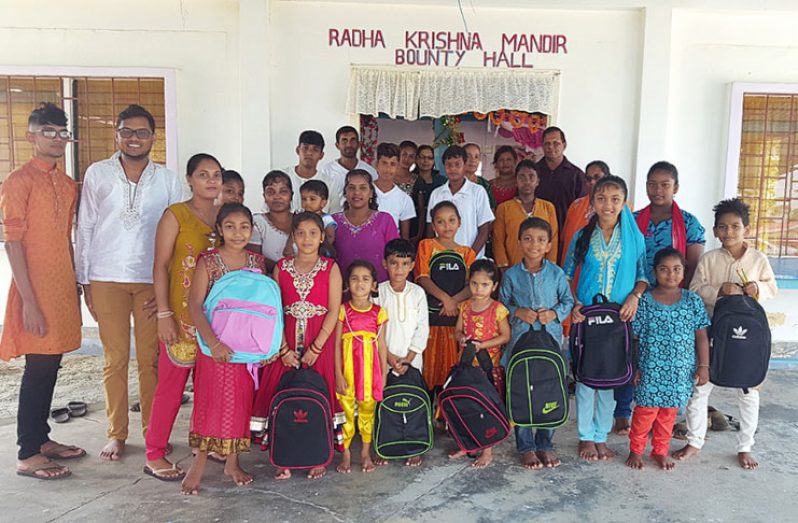 Leaders of the Essequibo Coast Dharmic Nawjawan with some of the children who benefited from the back-to-school drive