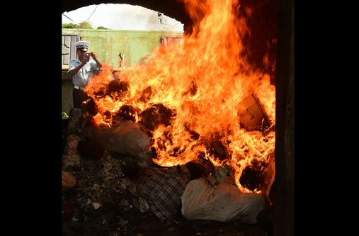 A police rank takes a picture of the drug in flames.