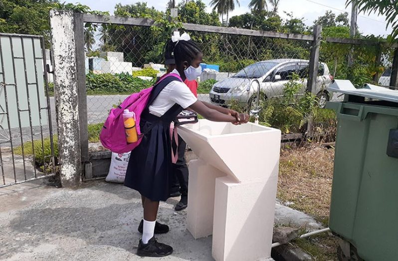 A Victoria Primary School pupil washing her hands before entering the school compound on Monday morning