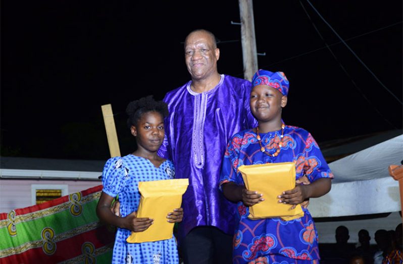 Two students from the village being presented with new electronic tablets from the Telecommunications Ministry
 (Samuel Maughn photo)