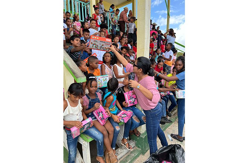 CEO Ms. Gomin Camacho shares toys to children at the Bartica Community Centre Ground