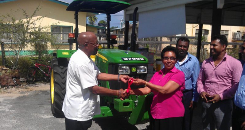 Minister of Local Government and Regional Development, Mr. Norman Whittaker formally hands over tractor keys to Tapakuma Toshao, Ms. Doreen Jacobus in the presence of Region 2 Chairman,Mr. Parmanand Persaud (behind Jacobus) and CARILED Project Coordinator, Mr. Dhanraj Singh