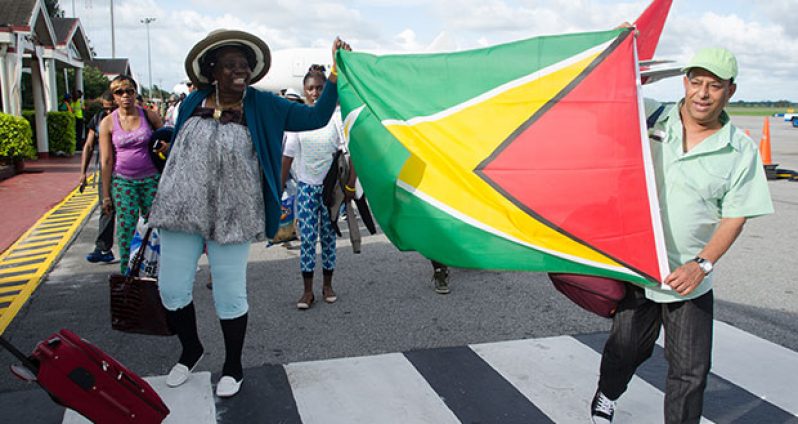 Returning Guyanese show their love for the country as they proudly display the
Golden Arrowhead shortly after disembarking Eastern Air Lines' innaugural flight to
Guyana on Friday (Alva Solomon photo)