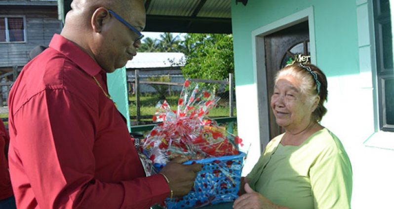 Minister within the Ministry of Finance, Juan Edghill handing over a hamper to another senior citizen in Linden