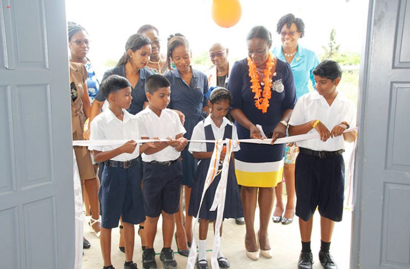 Minister Henry and pupils of Champagne Primary School cutting the ceremonial ribbon to commission the new building. (MOE photo)
