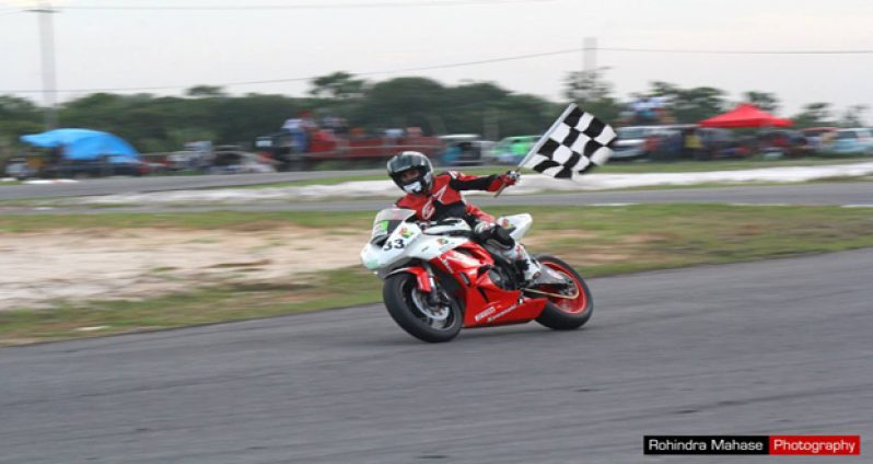 Elliot Vieira waves the chequered flag as he comes around the gooseneck (Rohindra Mahase Photography )