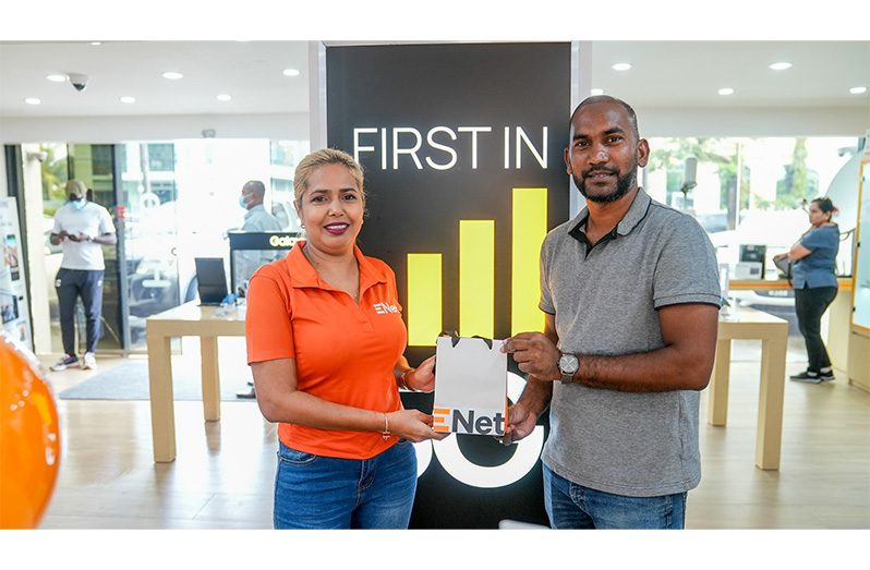 Co-Director of Kares One Guyana T10 Blast, Yusuf Ali, collects the cellphones from Nichola Parasram, Trade mobile coordinator at Enet