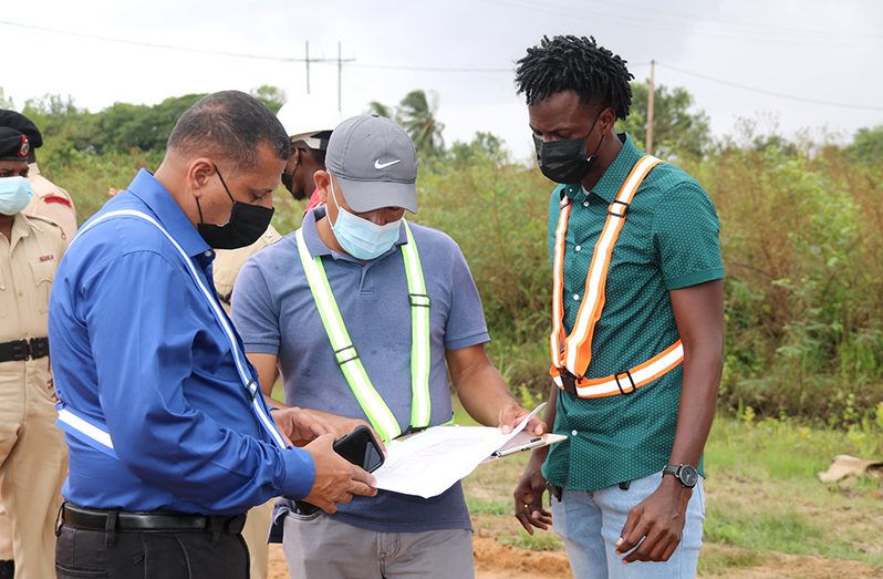 Housing and Water Minister, Collin Croal, with engineers from the projects department perusing the site map for the houses being constructed
