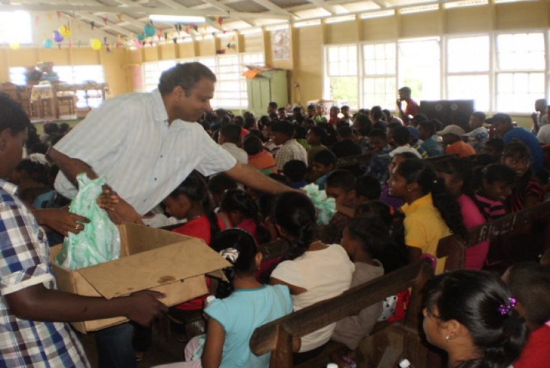 Minister Dr. Frank Anthony giving out snacks at the party for children in Enmore