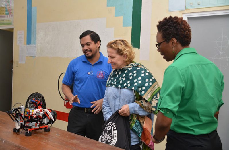 Senior Master and Head Coach for the STEM Club at the Three Miles Secondary School, Ron Ghanie explains the functions of one of the robots to Italian Special Envoy, Caterina Bertolini as Juanita Thomas from the Office of Climate Change looks on (DPI photo)