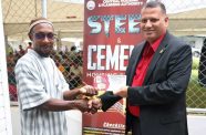 Minister of Housing and Water Collin Croal hands over a steel and cement subsidy voucher to recipient, Eon Allen