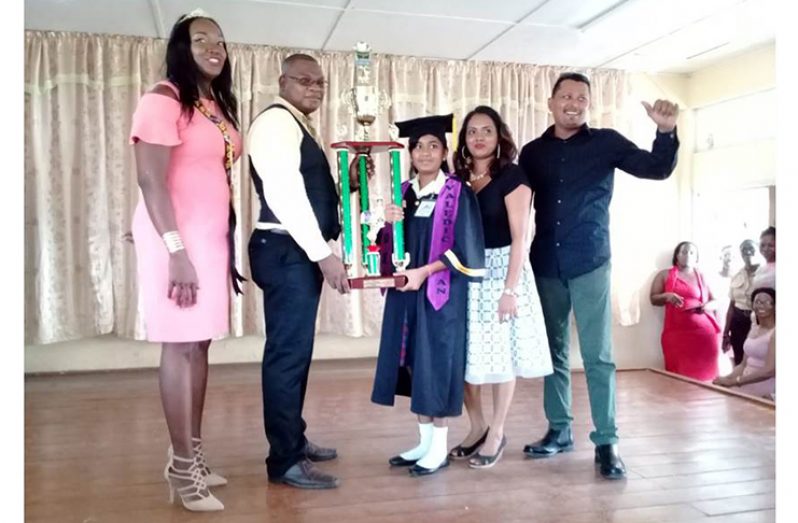 Teachers of New Diamond/Grove Primary School Robin Wilson and Colis Dublin as they presented a trophy to Esha Lakeram for her excellent performance while her parents Shareema and Kumar Lakeram looked on.