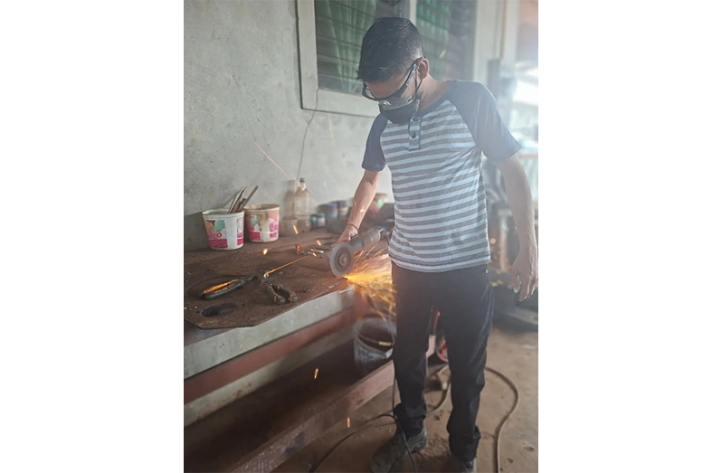 Eshwar in his workshop, operating a welding machine