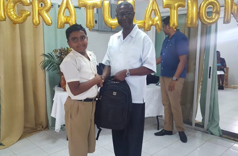 Regional Executive Officer Rupert Hopkinson presenting a backpack to a Top Performer Muneshwar Beepat, on behalf the Region at a recent honouring ceremony