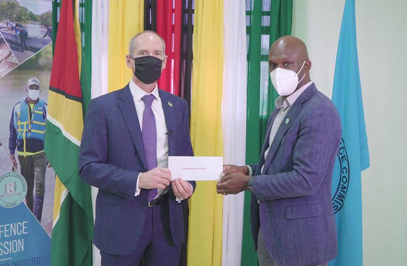 President of ExxonMobil Guyana, Alistair Routledge, handing over the cheque to Director-General of the CDC, Lieutenant Colonel Kester Craig, at the CDC headquarters on Wednesday