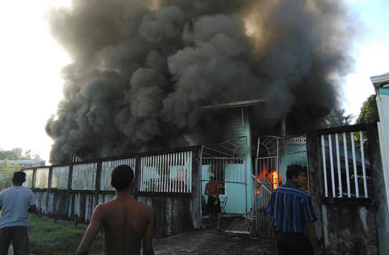 Thick smoke billowing from the early-morning fire as neighbours look on (photo credit: Sharaz Aswin)