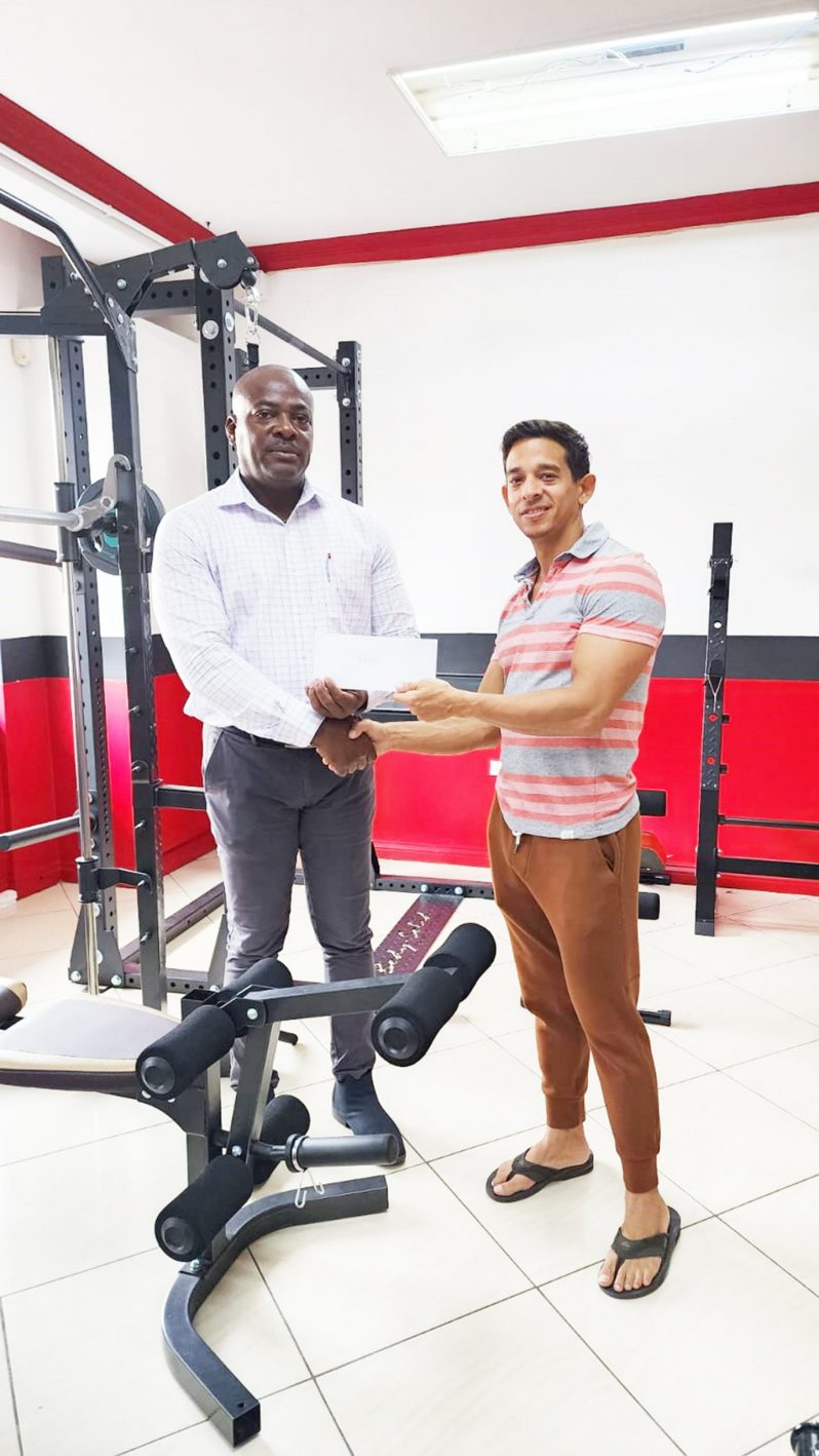 Jamie Mc Donald, owner of Fitness Express hands over sponsorship to President of the Guyana Amateur Powerlifting Federation (GAPLF), Franklyn Wilson