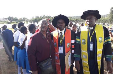 Dr. Joy Agard-Mighty in Uganda with Academic Registrar Mr Magara Silver and Vice-chancellor Rev. Fr. Dr. Deus Karemire (Students in the background)