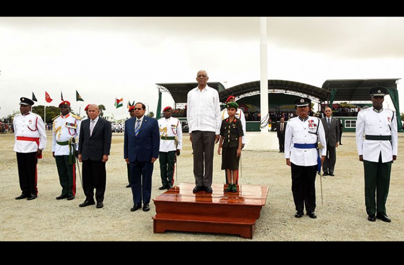 President David Granger stands at attention on the dais during the rendering  of the National Anthem at the start of the proceedings at the Jubilee Park on Friday. Doing likewise are heads of the Joint Services and Prime Minister Moses Nagamootoo and Minister of Social Cohesion, Dr George Norton