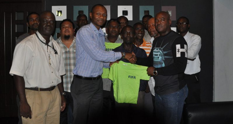 GFF executive member Dion Inniss (left) hands over one of the tops to EBFA president Franklin Wilson in the presence of fellow Executive and General Council members.