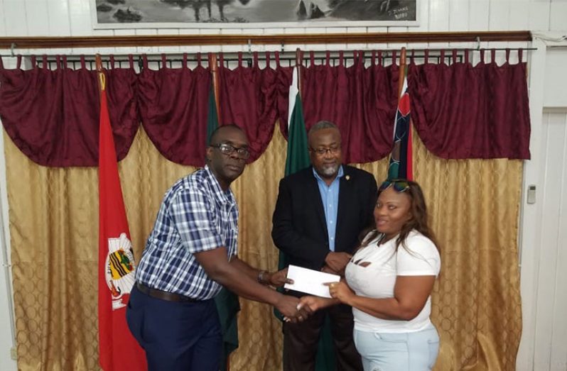 Deputy Commissioner Nigel Hoppie hands over a cheque to one of the recipients in the presence of Chairman of the Foundation, Reverend Dr Murtland Raphael Massiah