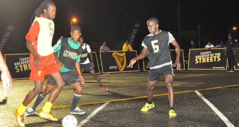Festival City’s key player, Daniel Favorite (red), is closely marked by North East LaPenitence Bevon Moseley and his teammate, during their exciting matchup in the sixth annual Guinness ‘Greatest of de Streets’ competition last Thursday night.