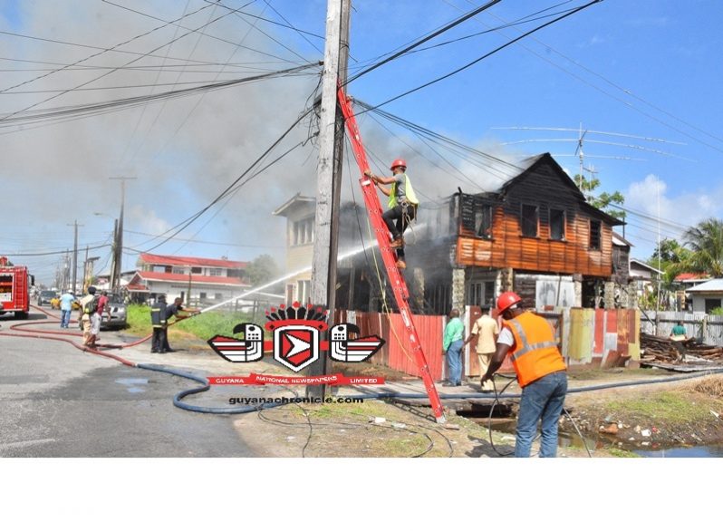 Technicians removed wires from electrical poles at the scene  as firemen fought the inferno on Monday morning. (Samuel Maughn photo)