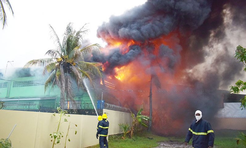 Firefighters battling the blaze at Mohammed and Son Trading, on Monday (Elvin Croker photo)