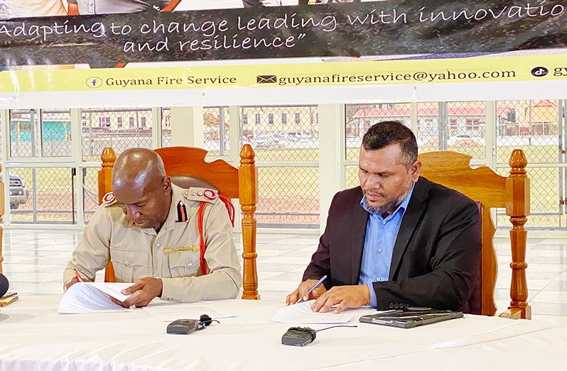 Chief Fire Officer, Gregory Wickham (left) and Chief Statistician, Errol La Cruez (right), sign the MoU  