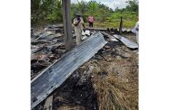 A Guyana Fire Service officer examines the scene of the fire as investigations continue into the blaze that destroyed a family’s home