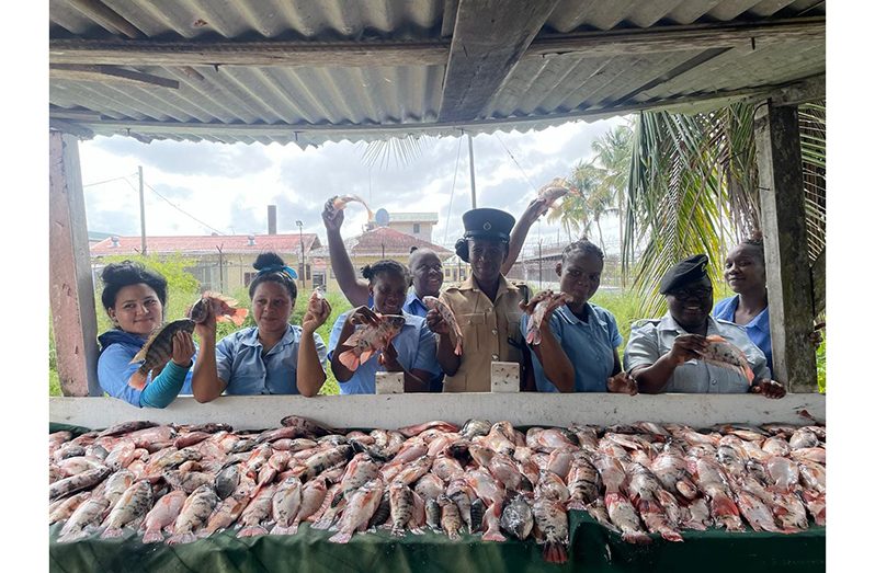 Female inmates, along with a prison officer, displaying tilapias from the Timehri Prison aquaculture project