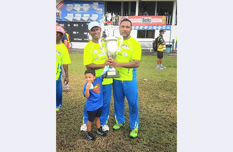Owner of Fisherman Masters, Pooran Singh, (left) and captain Zameer Hassan pose with the prestigious 2020 PM T20 Cup trophy.