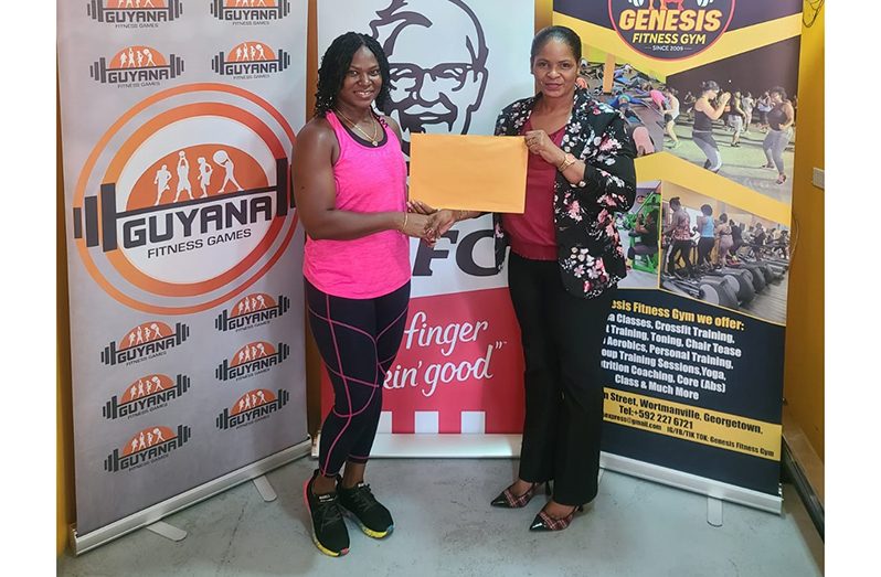 Co-ordinator Noshavayah King (left) collects the sponsorship from KFC Guyana Marketing Manager, Pamella Manasseh