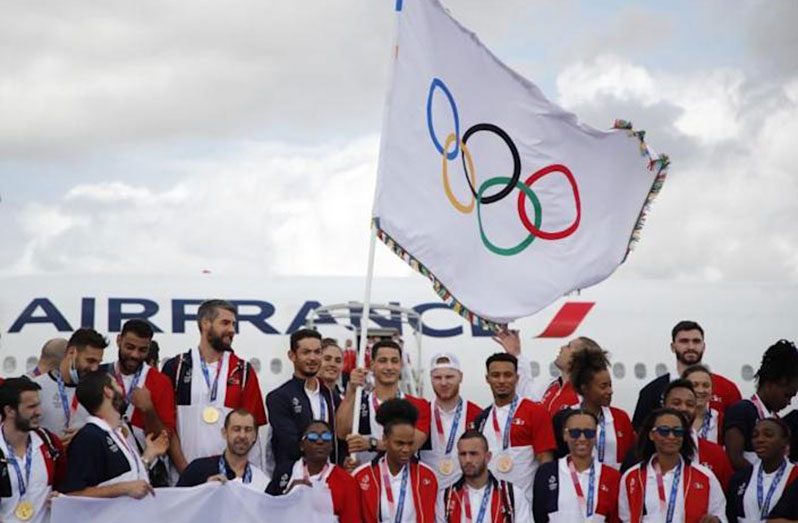 French Olympic medallists arrive with the Olympic flag in Paris.